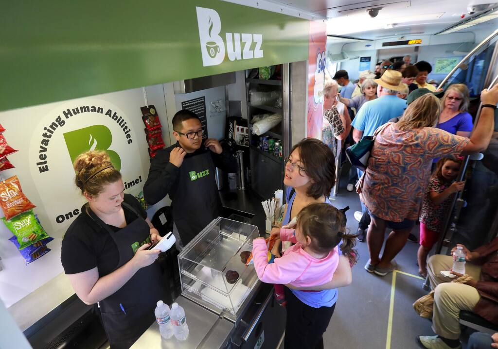 Michelle Stoffer of Corte Madera orders a snack for her daughter Nora, 2, from Meghan Harris and Jay Jay Rico at BI Buzz on the SMART train during a free ride day on Thursday, July 13, 2017. Becoming Independent will begin employing adults with disabilities in the train concession when train service kicks off later this year. (JOHN BURGESS/ PD)