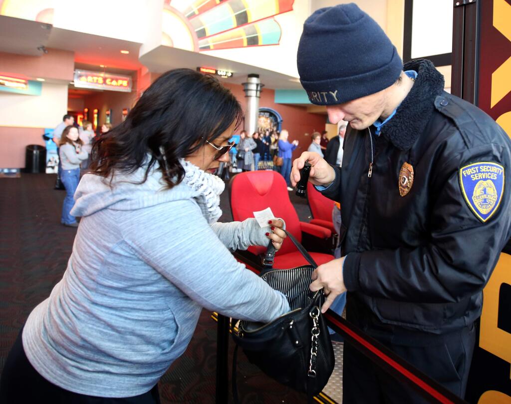 Security guard Thomas Tilley, right, searches the bag of Tracy Low, left, at the Boulevard 14 Cinemas in Petaluma, Thursday, December 25, 2014. Tilley was brought in to take extra precautions due to the threats around the release of 'The Interview.' (Crista Jeremiason / The Press Democrat)
