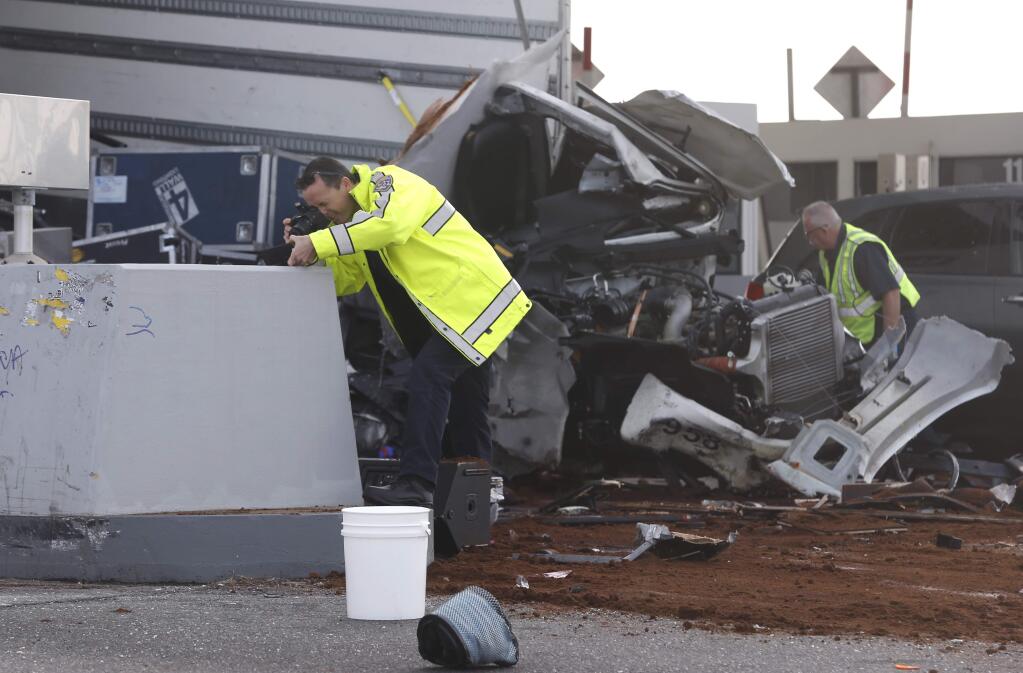 California Highway Patrol investigators gather evidence at the Bay Bridge toll plaza after a truck rammed through toll booth 14, killing the toll collector inside, before dawn in Oakland, Calif. on Saturday, Dec. 2, 2017. The two occupants of the truck were reportedly ejected from the vehicle. (Paul Chinn/San Francisco Chronicle via AP)