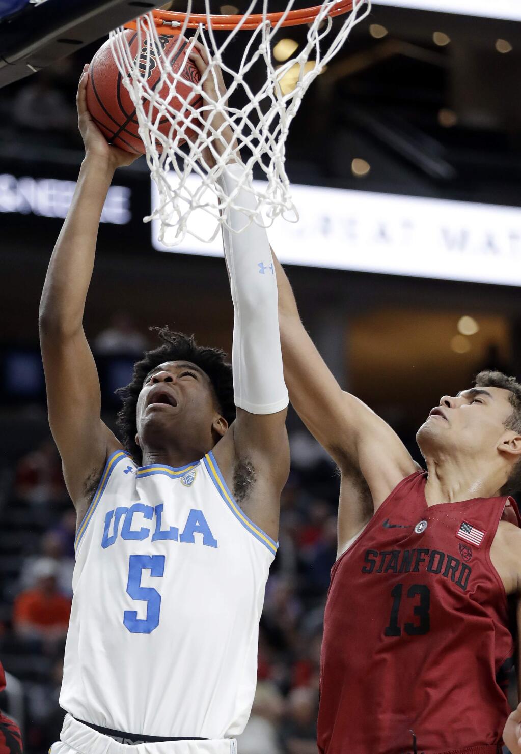 UCLA's Chris Smith (5) shoots while covered by Stanford's Oscar da Silva (13) during the first half of an NCAA college basketball game in the quarterfinals of the Pac-12 tournament Thursday, March 8, 2018, in Las Vegas. (AP Photo/Isaac Brekken)