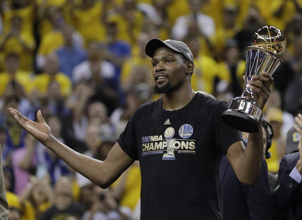 FILE - In this June 12, 2017, file photo, Golden State Warriors forward Kevin Durant gestures as he holds the Bill Russell NBA Finals Most Valuable Player Award after Game 5 of basketball's NBA Finals between the Warriors and the Cleveland Cavaliers in Oakland, Calif. A person with direct knowledge of the decision says Kevin Durant has declined to opt in for the second year of his contract with Golden State as expected, and will become an unrestricted free agent. Durant now must work out a new deal with the Warriors when free agency begins Saturday, the person said, speaking on condition of anonymity Thursday, June 29, 2017, because Durant's choice had not been formally announced. (AP Photo/Marcio Jose Sanchez, File)