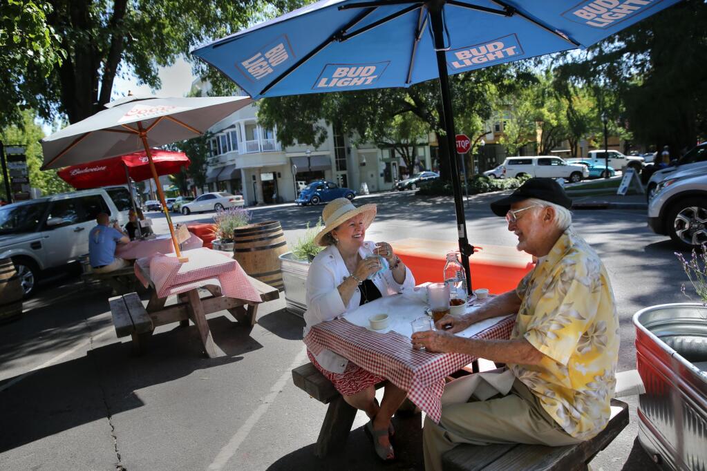 Healdsburg residents Caryl and George DeMerritt sit at an outdoor table at KINSmoke barbecue restaurant on the Healdsburg Plaza in Healdsburg, California, on Monday, July 27, 2020. (Beth Schlanke /The Press Democrat)