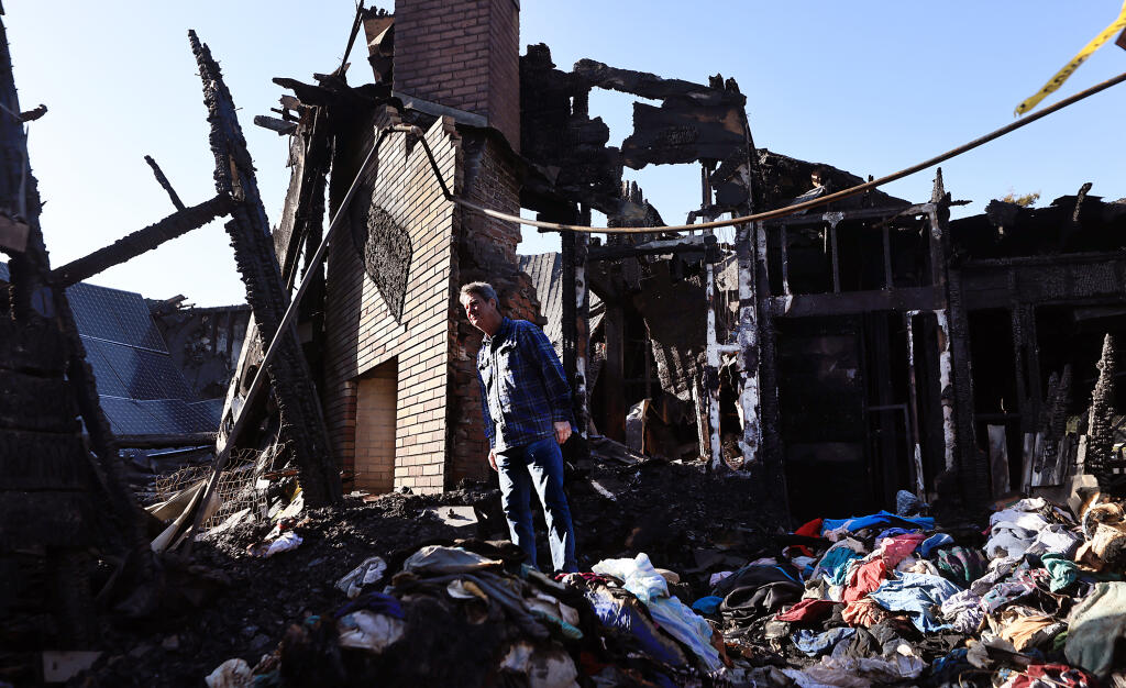 Kevin Evans, the president of the Gualala Community Center, peers through the burned remains of the Gualala Community Center, Tuesday, Feb. 14, 2023, after a fire ripped through the building early Monday morning.  (Kent Porter/The Press Democrat)