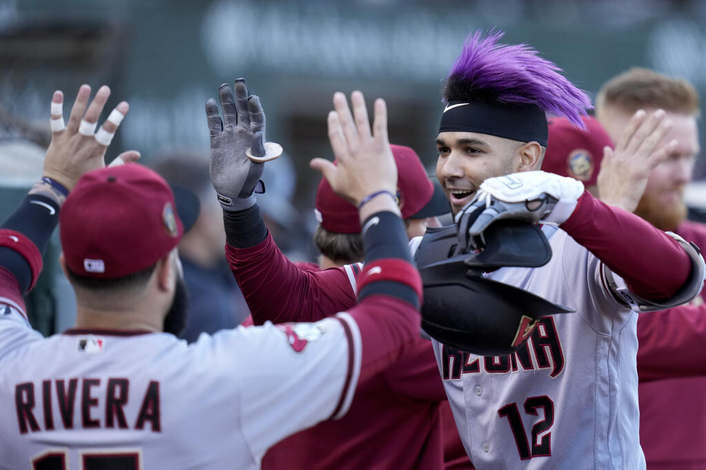 Arizona Diamondbacks' Lourdes Gurriel Jr., front right, celebrates at the dugout with Emmanuel Rivera, left, after hitting a two-run home run against the Oakland Athletics during the third inning of a baseball game in Oakland, Calif., Monday, May 15, 2023. (AP Photo/Godofredo A. Vásquez)