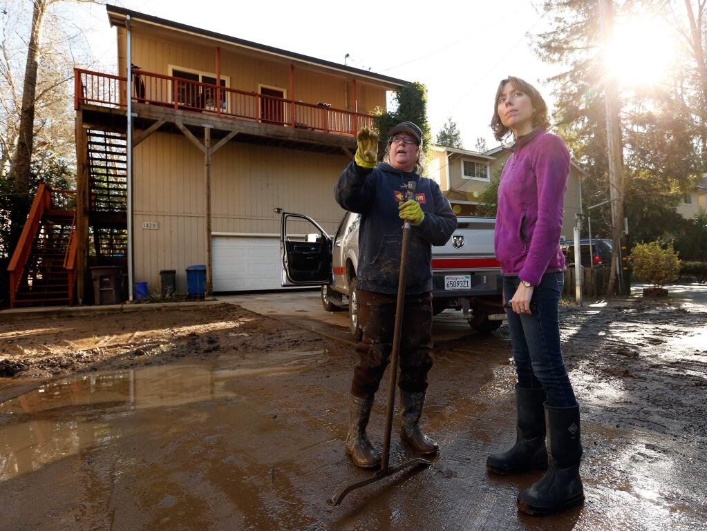 Wendy Bignall, left, pauses from cleaning mud off the street of her Mill Street neighborhood, known to locals as 'Submarine Flats,' to talk with county supervisor Lynda Hopkins as she and other county officials tour flood damaged areas along the lower Russian River, in Guerneville, California on Saturday, January 14, 2017. (Alvin Jornada / The Press Democrat)