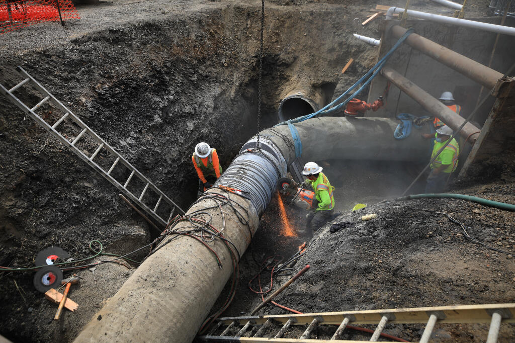To fit an elbow together, a crew from Ghilotti Construction Company cut off a section of water pipe to make the ends meet, Tuesday, July 21, 2020 in Petaluma. (Kent Porter / The Press Democrat) 2020