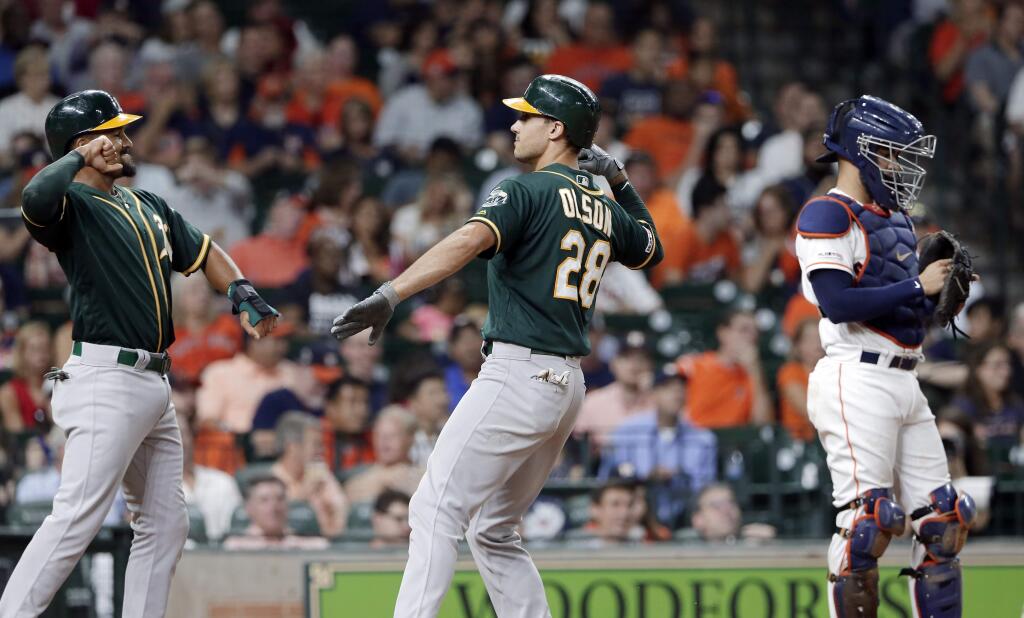 Oakland Athletics Marcus Semien, left, and Matt Olson, center, celebrate at the plate next to Houston Astros catcher Robinson Chirinos, right, after they scored on a two-run home run by Olson during the third inning Thursday, Sept. 12, 2019, in Houston. (AP Photo/Michael Wyke)