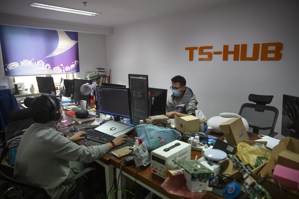 Workers wear face masks as they work in the offices of a tech company in Beijing, Wednesday, March 18, 2020. China's government has encouraged firms to open for business to restart the nation's economy as the number of new cases of coronavirus reported in the country continues to fall. The virus causes only mild or moderate symptoms, such as fever and cough, for most people, but severe illness is more likely in the elderly and people with existing health problems. (AP Photo/Mark Schiefelbein)