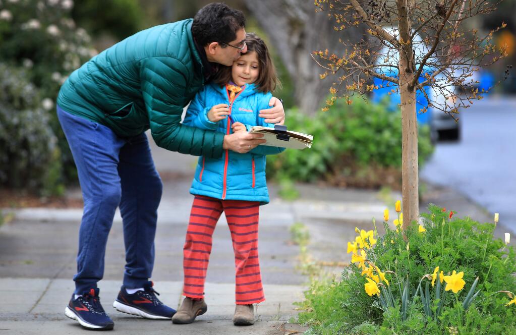 Angel Casas-Eragea congratulates his daughter Feliciana, 6, on finishing her homework assignment from Summerfield Waldorf School, Wednesday, March 18, 2020 in Santa Rosa. The two counted the number of flowers they saw took practice her counting. (Kent Porter / The Press Democrat) 2020