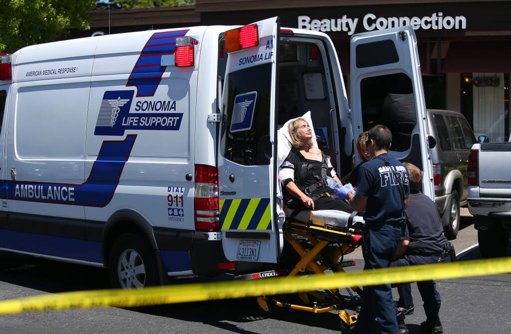 Emergency personnel place a woman injured in a Santa Rosa jewelry store robbery into an ambulance. (CHRISTOPHER CHUNG / The Press Democrat, 2014)