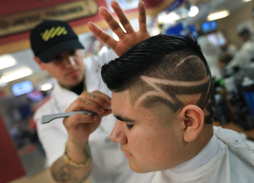 JayTee the Barber (Jose Tapia) gives a one-of-a-kind hair style to Francisco Hernandez, 12, at West Coast Cuts in Santa Rosa on Monday, Aug. 14, 2017. (KENT PORTER/ PD)