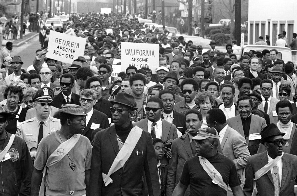 The Rev. Ralph David Abernathy, head of the Southern Christian Leadership Conference, lower right, leads a memorial march through downtown Memphis, Tennessee, April 4, 1969, in memory of Dr. Martin Luther King Jr., who was killed the year before. On the front row with Abernathy was Jerry Wurf, at left, president of the American Federation of State, County and Municipal Employees. (AP Photo/Fred Waters)