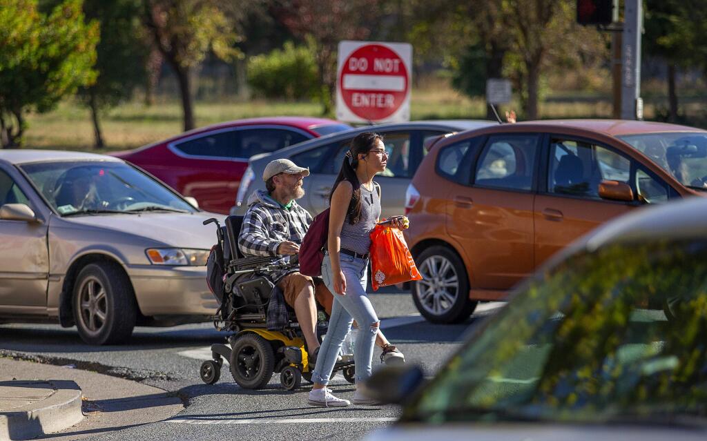 A disabled man in a wheelchair and a pedestrian try to make their way across Stony Point Rd. at the Hwy 12 exit ramp on Tuesday afternoon. Jennell Marie Davies, 39, of Santa Rosa was struck and killed by a truck while walking in the same crosswalk last Tuesday, October 23, 2018. (photo by John Burgess/The Press Democrat)