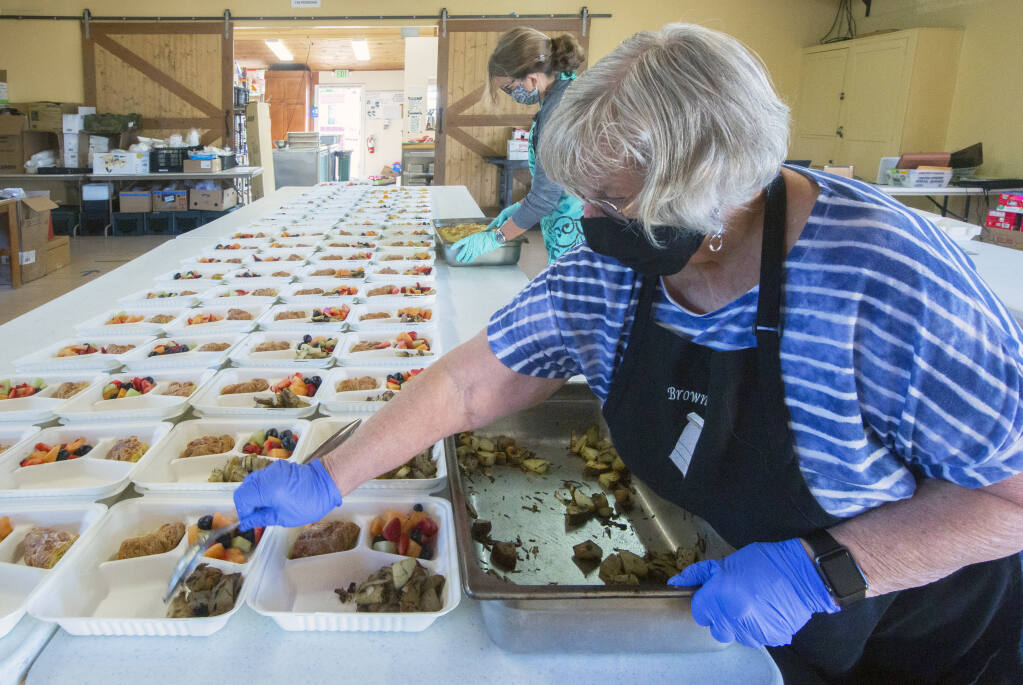 Patti England, foreground, and Marina Zachau, both volunteers for Sonoma Overnight Support (SOS), help prepare some of the hundreds of meals offered by the nonprofit every day. (Photo by Robbi Pengelly/Index-Tribune)