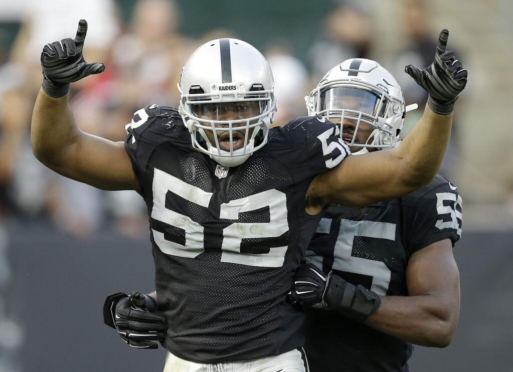 FILE - In this Sunday, Dec. 7, 2014, file photo, Oakland Raiders outside linebacker Khalil Mack (52) celebrates after sacking San Francisco 49ers quarterback Colin Kaepernick with outside linebacker Sio Moore during the fourth quarter of an NFL football game in Oakland, Calif. The arrival of coach Jack Del Rio's new staff, upgrades made through free agency and a foundation led by last year's top two draft picks, quarterback Derek Carr and linebacker Khalil Mack, have given the Raiders more reasons for optimism that usual heading into training camp (AP Photo/Ben Margot, File)