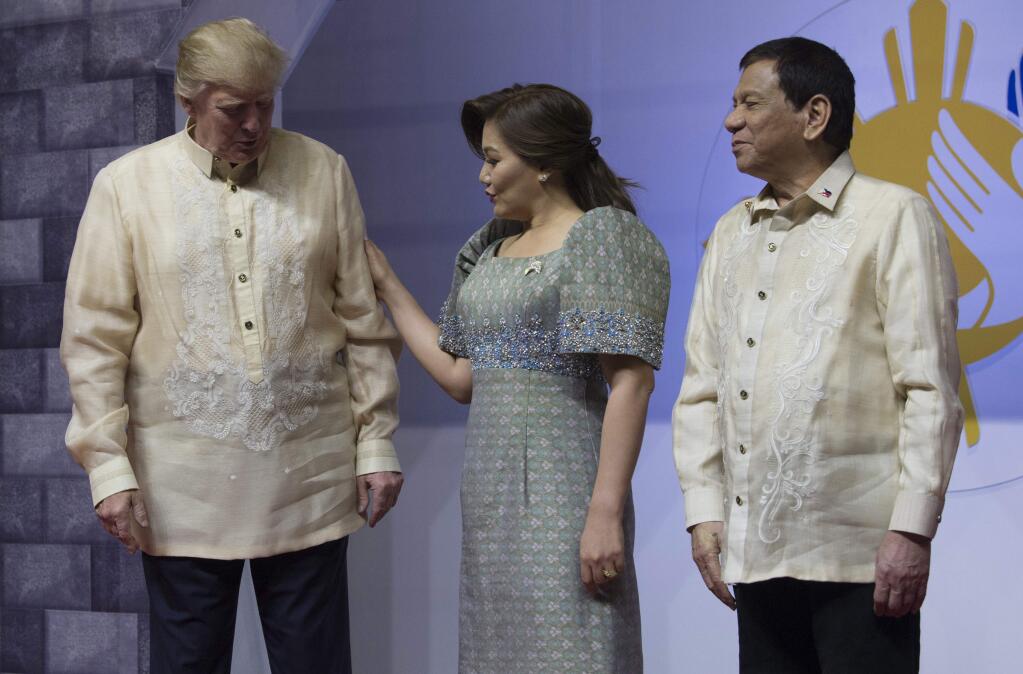 Philippines President Rodrigo Duterte, right, and partner Honeylet Avancena, center, greet President Donald Trump as he arrives ASEAN Summit dinner in Manila, Philippines on Sunday, Nov. 12, 2017. (Adrian Wyld/The Canadian Press via AP)