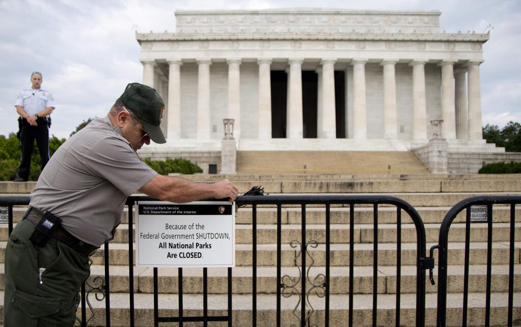 A National Park Service employee posts a sign on a barricade closing access to the Lincoln Memorial during a government shutdown in 2013. (CAROLYN KASTER / Associated Press)