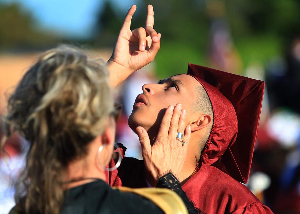 Piner High School counselor Susan Jablonski, comforts Arnie Mendoza as he points skyward after receiving his diploma Friday, June 1, 2018 during Piner's graduation. Both were appreciative of his achievements while at Piner. (Kent Porter / The Press Democrat) 2018