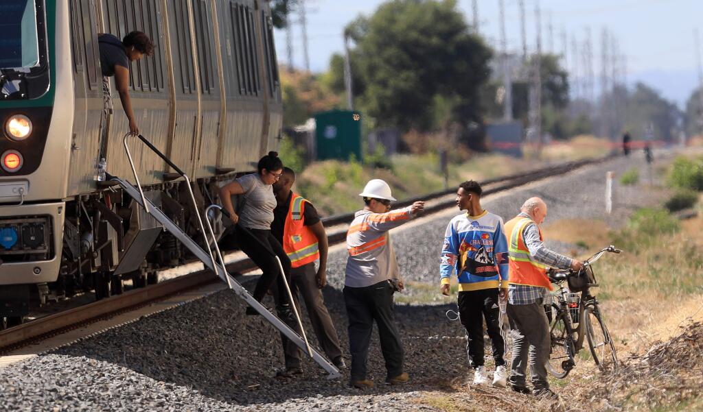 Passengers are escorted off a SMART train between San Miguel and Piner Roads, Friday, July 12, 2019, after the train struck a pedestrian on the tracks near San Miguel Road. (KENT PORTER/ PD)