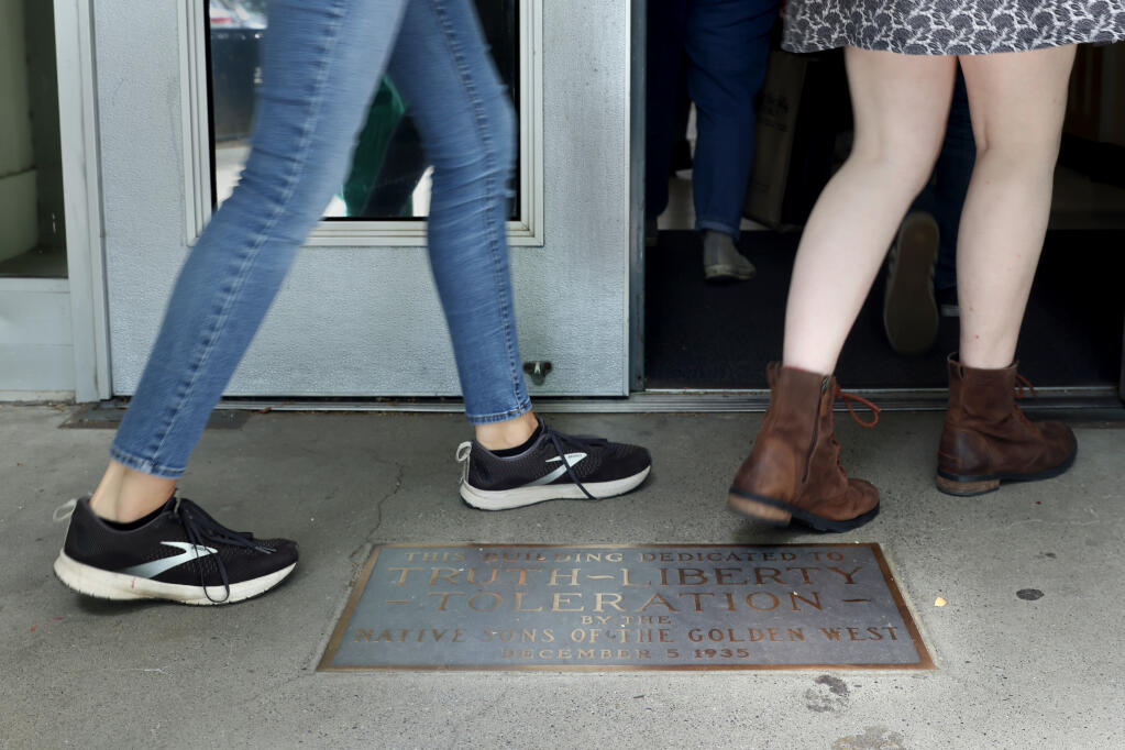 Students walk past a plaque that reads, "This building dedicated to Truth, Liberty, Toleration by the Native Sons of the Golden West," which sits just before the front door of the main classroom building at West County High School in Sebastopol on Thursday, May 5, 2022.(Beth Schlanker/The Press Democrat)