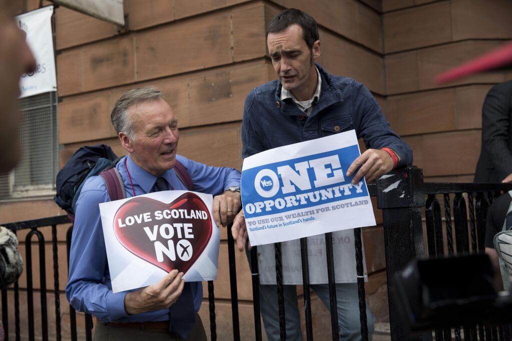 A No campaign supporter and a Yes campaign supporter chat holding posters after a No campaign event where a number of speeches were made by different people and politicians in Glasgow, Scotland, Wednesday, Sept. 17, 2014. Will the ayes have it, or will Scotland say naw thanks? No one is certain. Excitement and anxiety mounted across the country Wednesday, the final day of campaigning before Thursday's referendum on independence. With opinion polls suggesting the result is too close to call and turnout expected to reach record levels, supporters of separation feel they are within touching distance of victory but wonder whether their surge in the polls will be enough. (AP Photo/Matt Dunham)