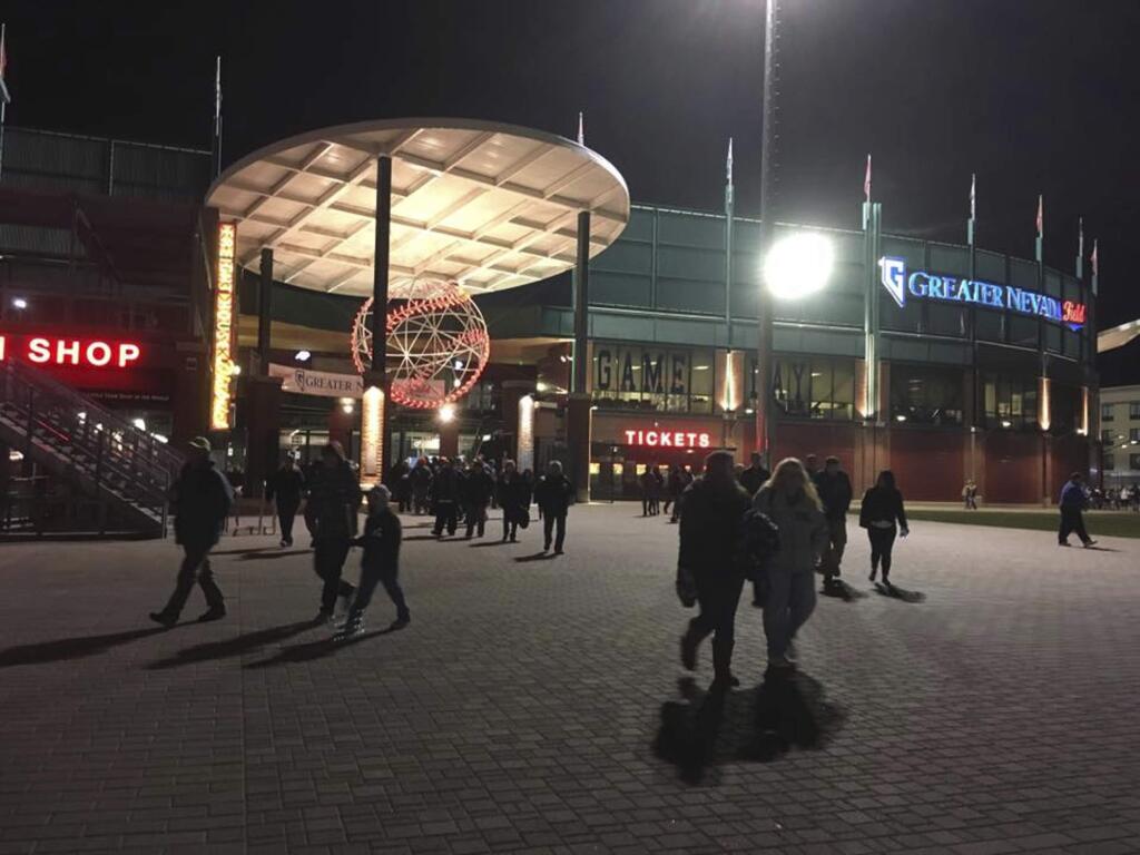 In this April 11, 2017 photo, fans walk outside Greater Nevada Field during last year's opening game for the Reno Aces minor league baseball team in Reno, Nev. A Nevada woman has declined an invitation to sign the national anthem at one of the Aces' games this summer because the team won't let her bring her gun. The woman said she wears the gun or keeps it in a purse because she doesn't feel safe walking at night in downtown Reno, where the stadium is located. (AP Photo/Scott Sonner)
