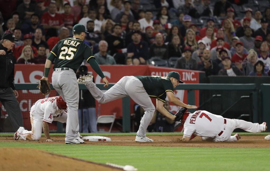 Oakland Athletics starting pitcher Kendall Graveman, center, tags out the Los Angeles Angels' Cliff Pennington, right, after tagging out Angels' Ben Revere, left, while Oakland's Ryon Healy watches during the fifth inning Thursday, April 27, 2017, in Anaheim. (AP Photo/Jae C. Hong)