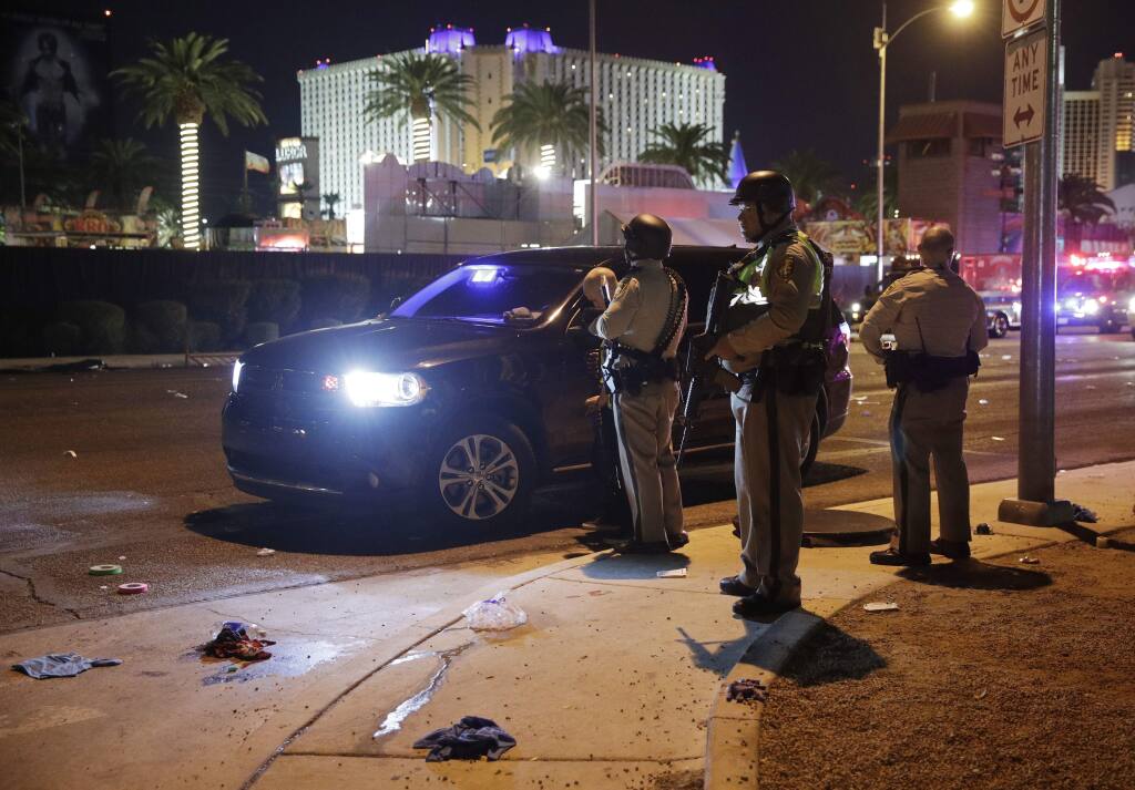 Las Vegas Police stand at the scene of a shooting along the Las Vegas Strip, Monday, Oct. 2, 2017, in Las Vegas. Multiple victims were being transported to hospitals after a shooting late Sunday at a music festival on the Las Vegas Strip. (AP Photo/John Locher)