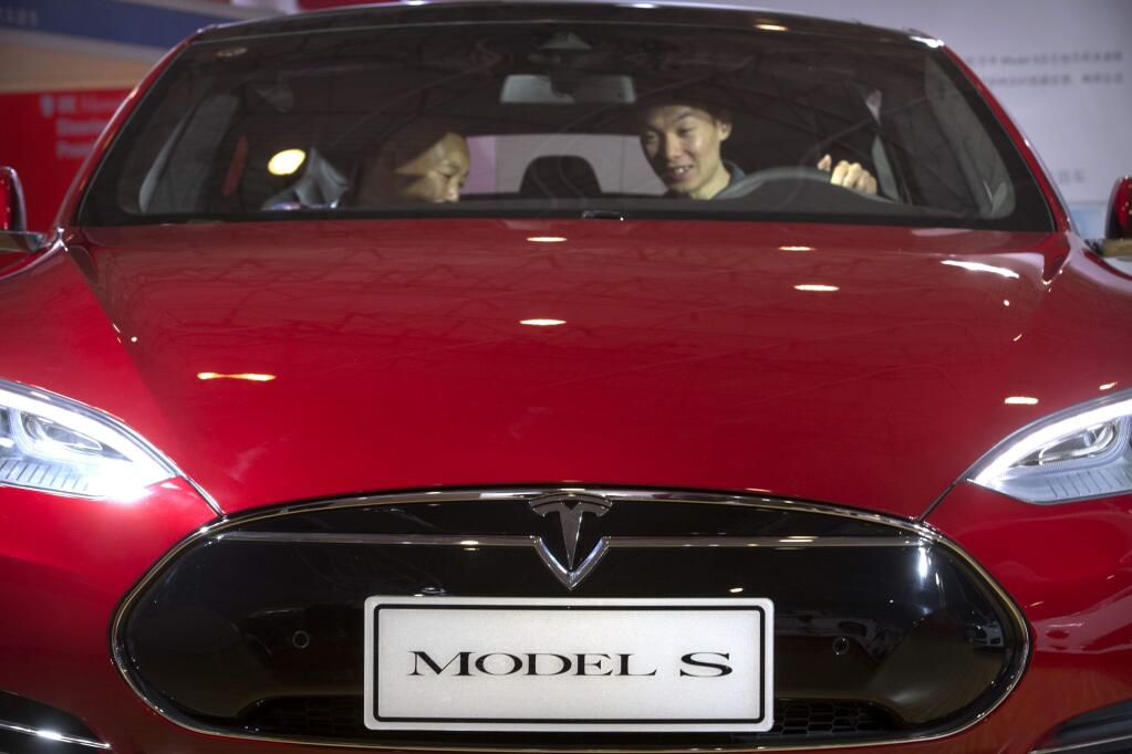 FILE - In this Monday, April 25, 2016, file photo, a man sits behind the steering wheel of a Tesla Model S electric car on display at the Beijing International Automotive Exhibition in Beijing. Federal officials say the driver of a Tesla S sports car using the vehicle's “autopilot” automated driving system has been killed in a collision with a truck, the first U.S. self-driving car fatality. The National Highway Traffic Safety Administration said preliminary reports indicate the crash occurred when a tractor-trailer made a left turn in front of the Tesla at a highway intersection. NHTSA said the Tesla driver died due to injuries sustained in the crash, which took place on May 7 in Williston, Fla. (AP Photo/Mark Schiefelbein, File)