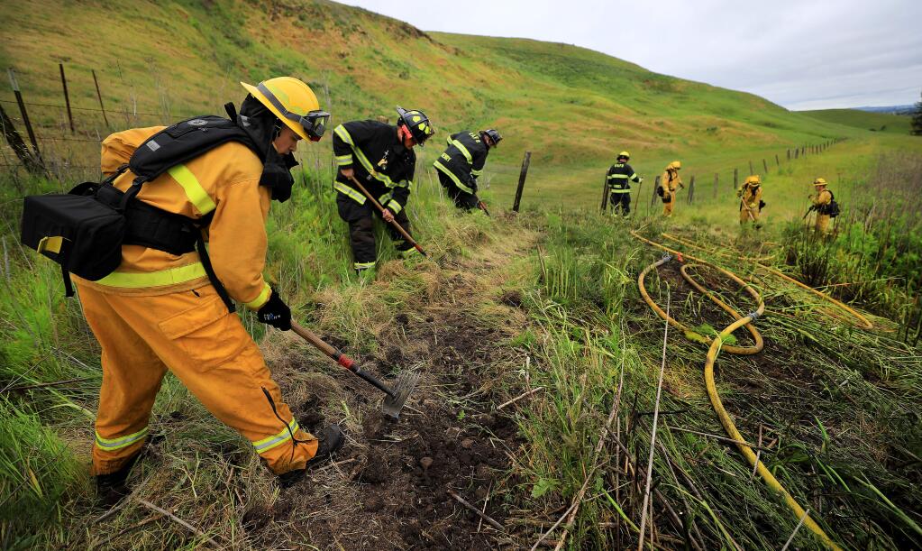 Rancho Adobe part-time firefighter James Norton cuts line around a small brush fire on the Cotati Grade with his colleagues and Cal Fire, Monday, May 6, 2019 near Petaluma. Norton was hired about six months ago. (Kent Porter / The Press Democrat) 2019