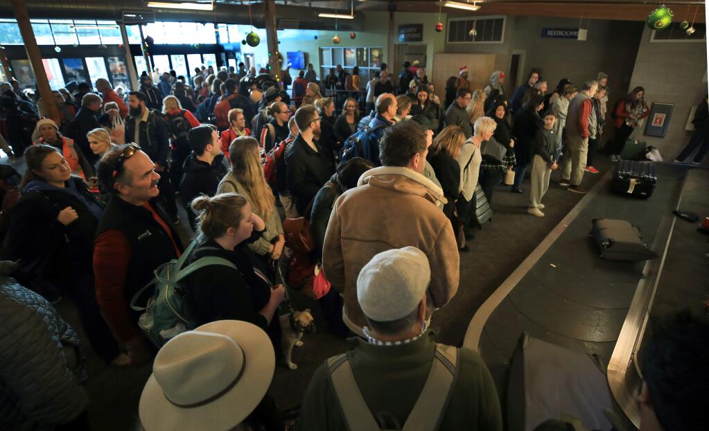 Passengers wait for their bags at the crowded terminal at the Charles M. Schulz Sonoma County Airport on Tuesday, Dec. 24, 2019. (Kent Porter / The Press Democrat) 2019