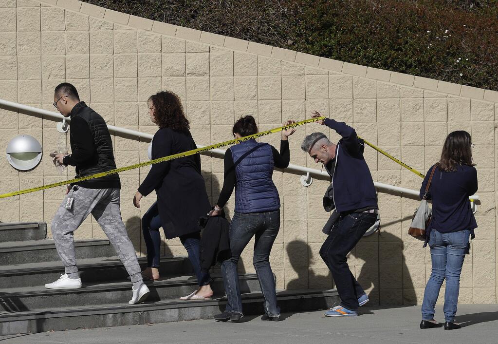 A group is escorted into a YouTube office building in San Bruno, Calif., Wednesday, April 4, 2018. A woman suspected of shooting three people at YouTube headquarters before killing herself was furious with the company because it had stopped paying her for videos she posted on the platform, her father said Tuesday, April 3, 2018. (AP Photo/Jeff Chiu)