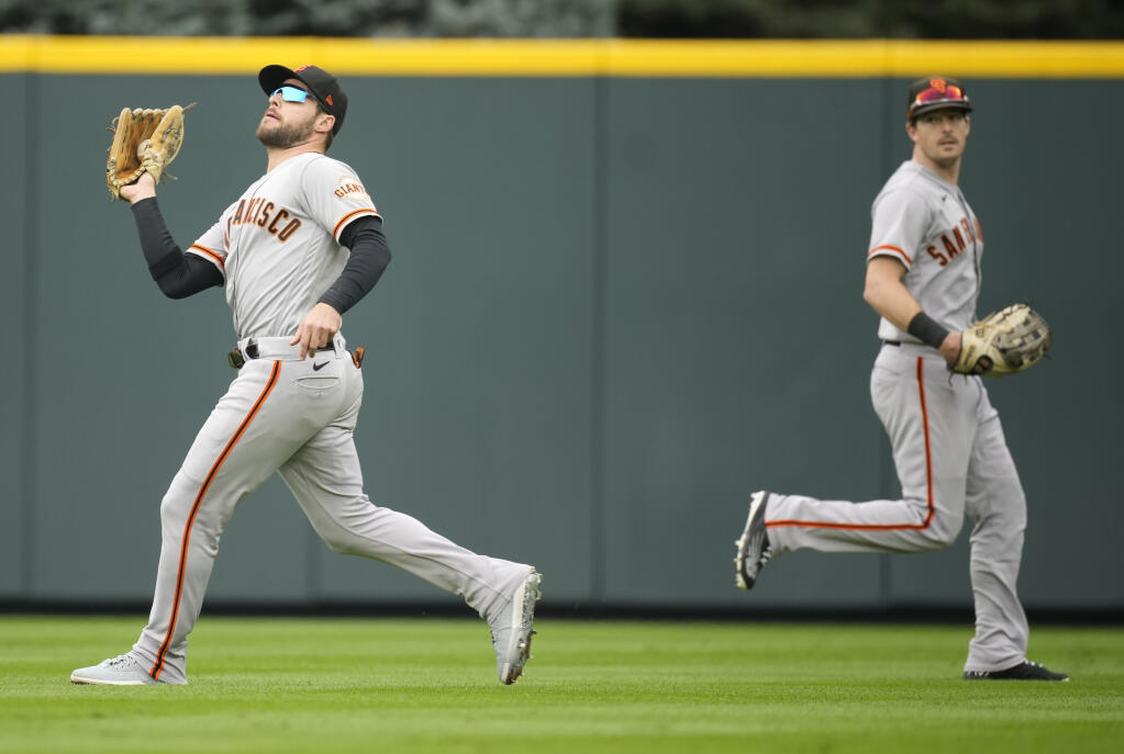 Giants right fielder Luis Gonzalez, front, pulls in a fly ball as center fielder Mike Yastrzemski looks on in the fourth inning against the Colorado Rockies, Thursday, Sept. 22, 2022, in Denver. (David Zalubowski / ASSOCIATED PRESS)