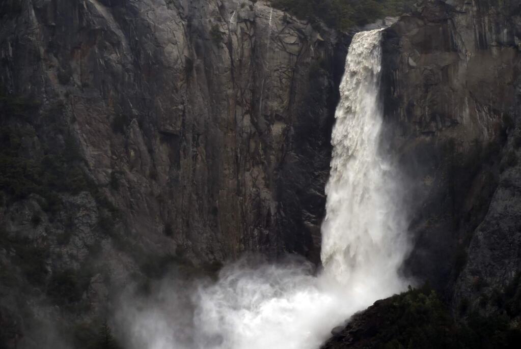 FILE - In this April 7, 2018, file photo, the raging Bridalveil Fall plummets into Yosemite Valley, while closed to the public due to a flooding Merced River, in Yosemite National Park, Calif. A Romanian tourist has died in a fall near the waterfall in Yosemite National Park on Wednesday, July 31, 2019. Authorities say 21-year-old Lucian Miu was scrambling on some wet rocks below Bridalveil Fall when he fell about 20 feet and later died at a hospital. The Fresno Bee says two other people were injured in separate falls in the park this week. (Eric Paul Zamora/The Fresno Bee via AP, File)