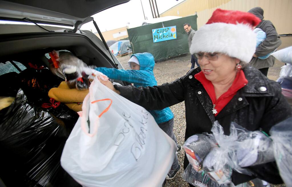 Nine year-old Janice Williams, left, helps distribute blankets, socks and supplies with Jenny Hirschi at Camp Michela in Santa Rosa, Monday Dec. 21, 2015. (Kent Porter / Press Democrat ) 2015