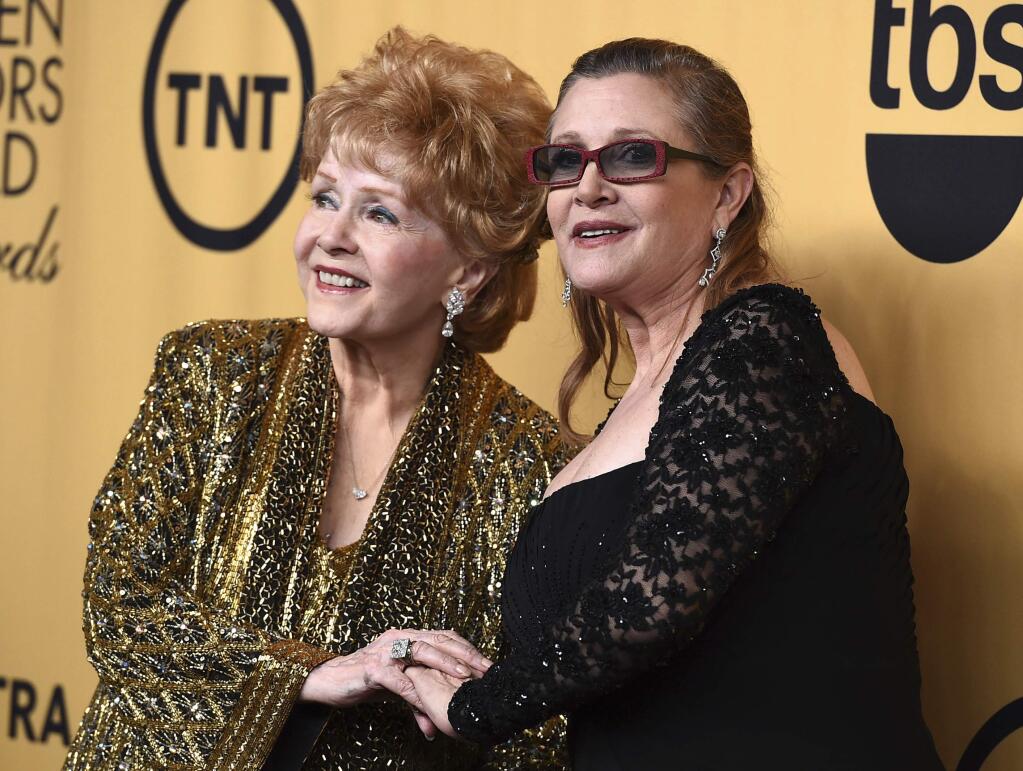 FILE - In this Jan. 25, 2015 file photo, Debbie Reynolds, winner of the Screen Actors Guild lifetime award, left, and Carrie Fisher pose in the press room at the 21st annual Screen Actors Guild Awards in Los Angeles. The mother-daughter actresses will be honored at a public memorial on Saturday, March 25, 2017, at the storied Hollywood Hills cemetery where both have been laid to rest. Fisher and Reynolds died one day apart in late December 2016. (Photo by Jordan Strauss/Invision/AP, File)