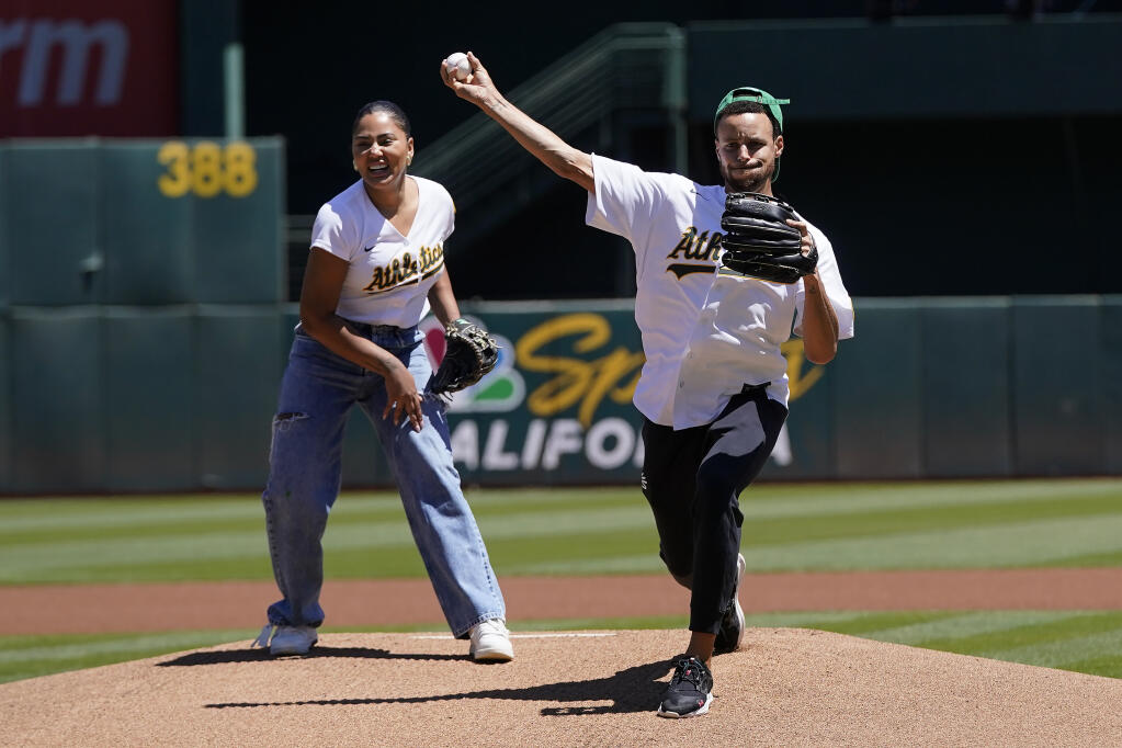 The Warriors’ Stephen Curry, right, and his wife, Ayesha Curry, throw out ceremonial first pitches before an A’ game against the Astros in Oakland on Wednesday, July 27, 2022. (AP Photo/Jeff Chiu)