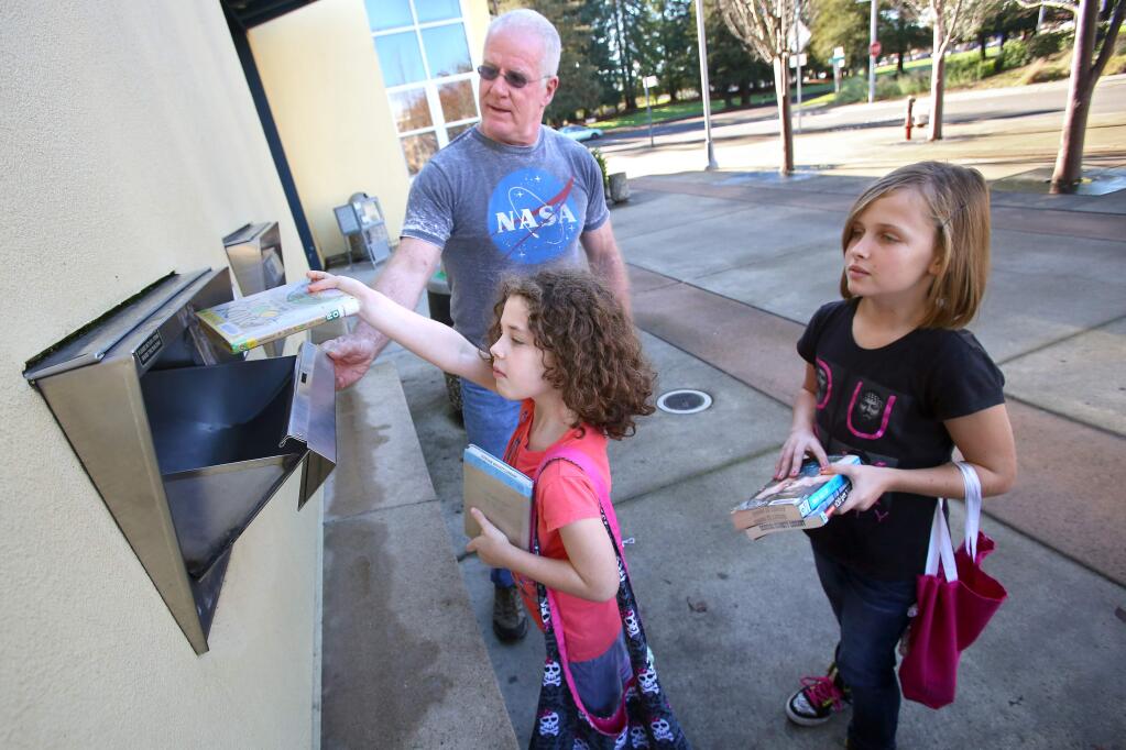 PHOTO: 2 BY CHRISTOPHER CHUNG/ THE PRESS DEMOCRAT -Rob Loughran helps his granddaughters Gwenyth, 8, left, and Gillian Maloney, 10, return books at the Rohnert Park-Cotati Regional Library in Rohnert Park last week. Loughran brought his granddaughters to get their Sonoma County Library cards last month.