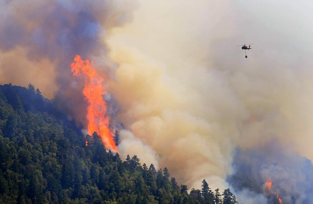 An Air National Guard helicopter moves in to make a water drop as the Lodge Fire between Leggett and Laytonville jumps the Eel River and moves upslope, Friday Aug. 8, 2014. (Kent Porter / Press Democrat)