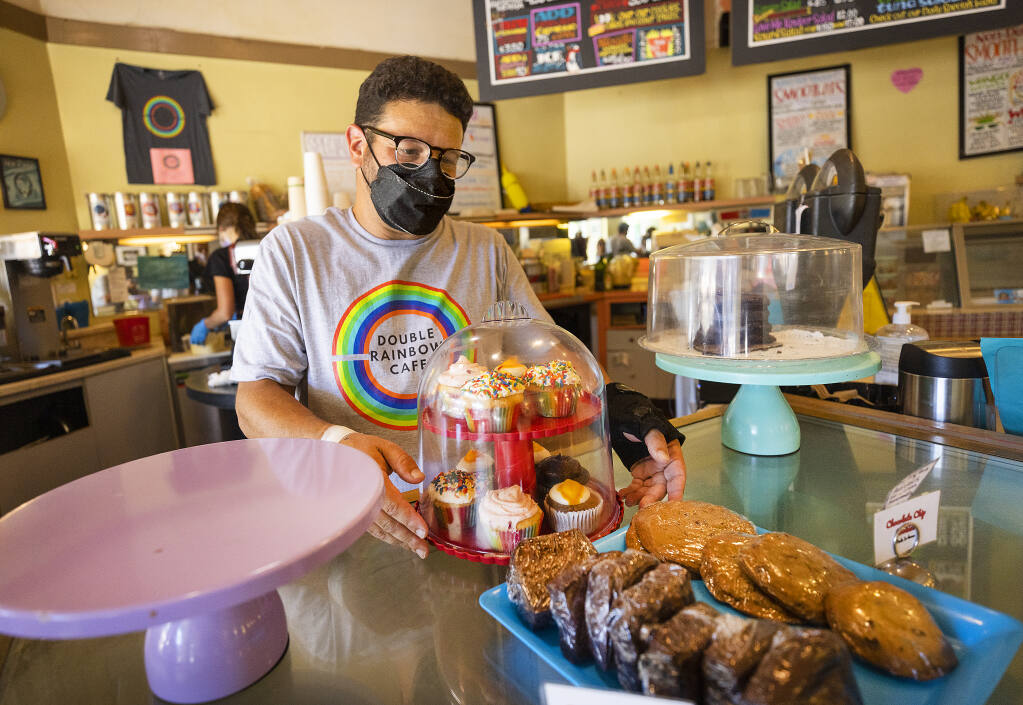 Forrest Manning, owner of the Double Rainbow Café in San Rafael fills the cupcake, cookie and cake display on Monday, Aug. 8. (John Burgess / for North Bay Business Journal)