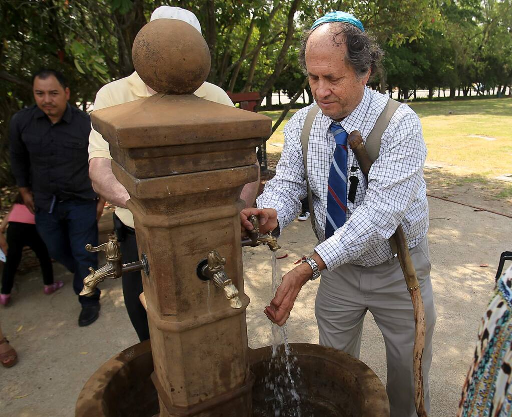 Dennis Judd cleanses his hands after the burial of his mother Lillian Judd, Wednesday June 8, 2016 at Santa Rosa Memorial Park in the Shomrei Torah Cemetery in Santa Rosa. A fixture in Sonoma County's Jewish community, Lillian Judd survived Auschwitz during the Holocaust in WWII. She was 93. The fountain was built by Dennis Judd as part of a memorial to his mother and others that are buried in the cemetery. (Kent Porter / Press Democrat) 2016