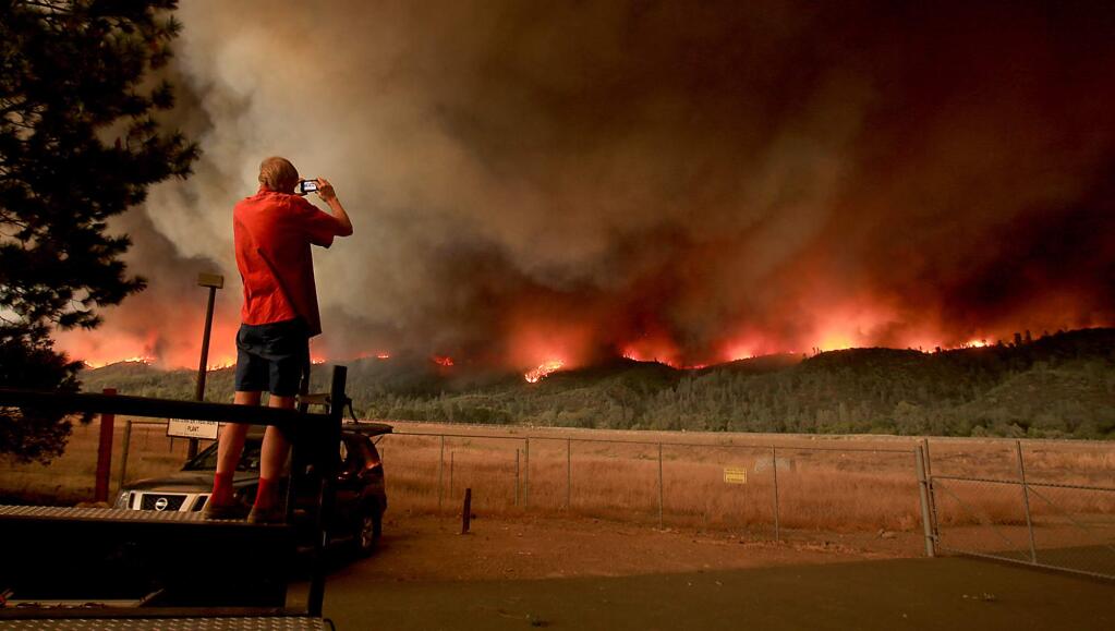 Cobb resident Michael Huber photographs the Valley fire as it rolls along on a 12 mile fire front as it heads to Middletown, on the slopes of Boggs Mountain in Lake County, Saturday Sept. 12, 2015. (Kent Porter / Press Democrat) 2015