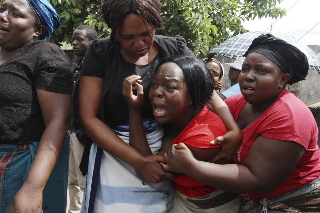 A family member of Kelvin Tinashe Choto reacts, during his funeral in Chitungwiza, about 30 kilometres south east of the capital, Harare, Zimbabwe, Saturday, Jan, 19, 2019. Before the family of Kelvin Tinashe Choto knew he had been killed, social media in Zimbabwe was circulating a photo of his battered body lying on the reception counter of a local police station. Angry protesters had left him there. The 22-year-old was shot in the head, one of at least a dozen people killed since Monday in a violent crackdown by security. (AP Photo/Tsvangirayi Mukwazhi)