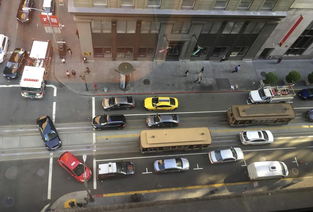 A fire truck at top left and other traffic try to make their way around a pair of idled cablecars on California Street after a large power outage Friday, April 21, 2017, in San Francisco. Pacific Gas & Electric says about 90,000 customers have been affected by the outage. The outage includes the Financial District and other areas. One downtown commuter rail station has been shut down. (AP Photo/Eric Risberg)