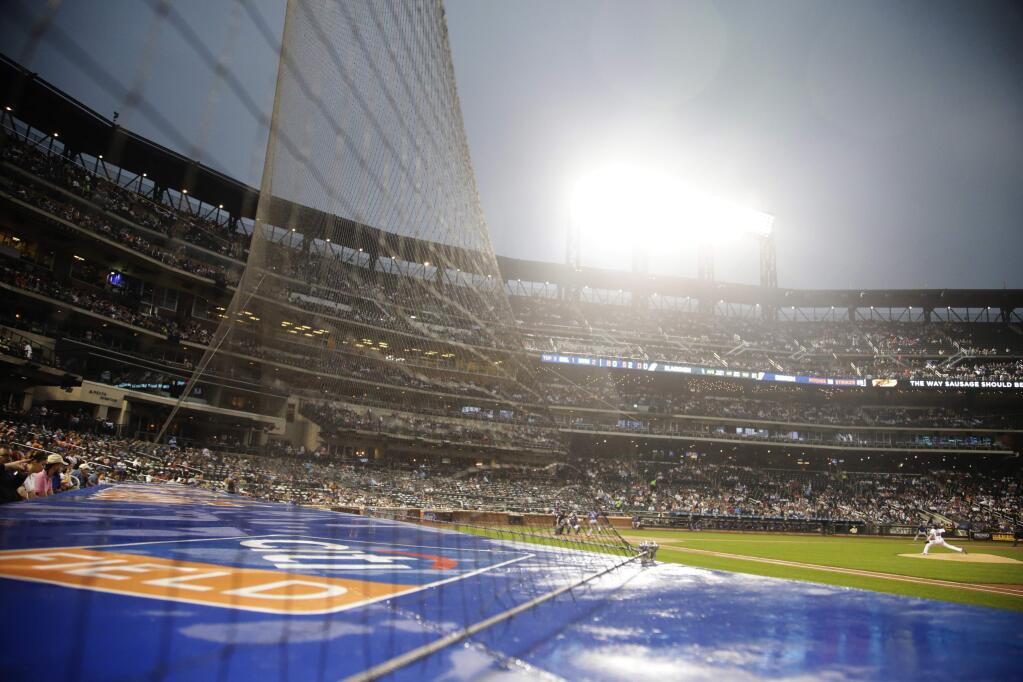 In this July 14, 2017 file photo, fans watch through a net as New York Mets Jacob deGrom delivers a pitch during the third inning against the Colorado Rockies in New York. The New York Yankees do not employ as much netting at Yankee Stadium. On Wednesday, Sept. 20, 2017 a young girl in the stands at Yankee Stadium had to be carried out after she was hit by a line drive. (AP Photo/Frank Franklin II, File)