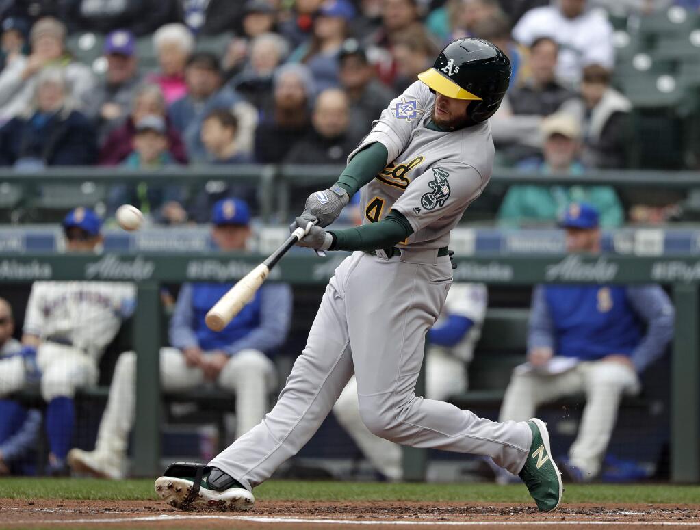 The Oakland Athletics' Jed Lowrie connects for a two-run home run against the Seattle Mariners in the first inning Sunday, April 15, 2018, in Seattle. (AP Photo/Elaine Thompson)