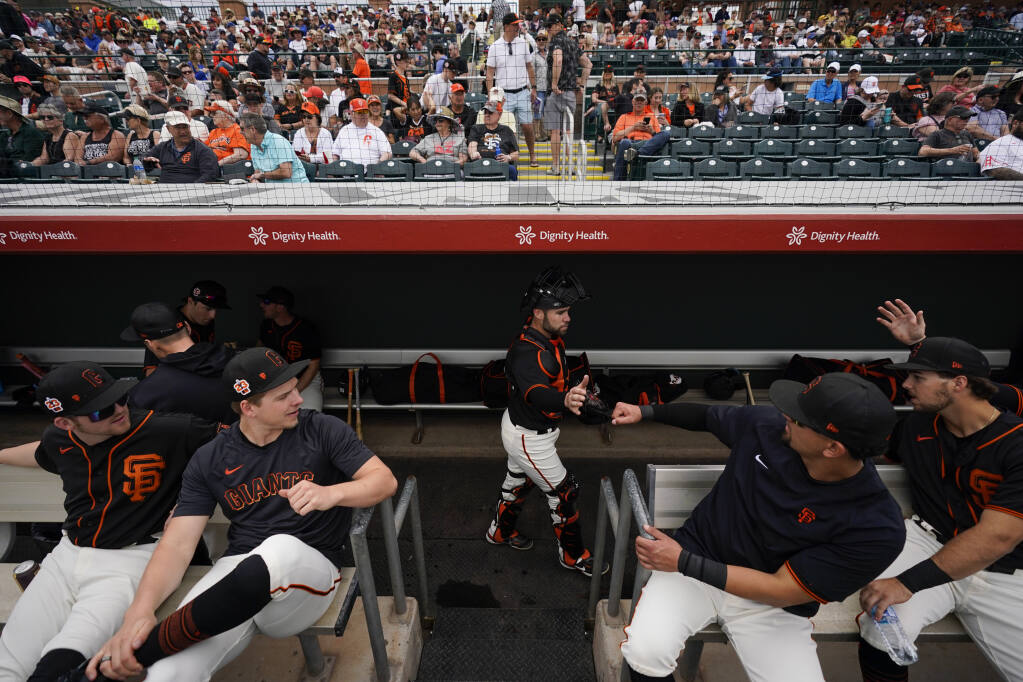 Giants catcher Austin Wynns, center, greets players in the dugout before a March 9 spring training game against the Milwaukee Brewers in Scottsdale, Arizona. (Ashley Landis / ASSOCIATED PRESS)