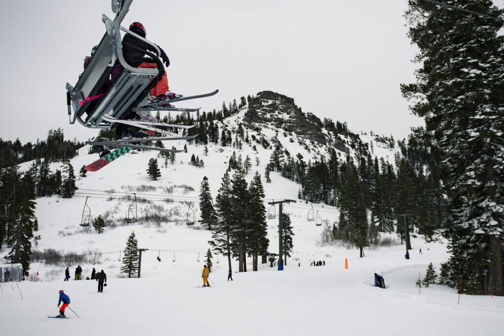 Skiers ride a chairlift at Alpine Meadows Ski Resort on Friday, Jan. 17, 2020, in front of the mountain traversed by the Subway Cirque ski run where one person was killed and another seriously injured in an avalanche earlier in the day. (Jason Pierce/The Sacramento Bee via AP)