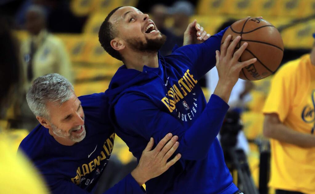 Stephen Curry, right, warms up with Bruce Fraser, assistant coach for player development, prior to the Warriors game with the Pelicans during the NBA Western Conference semifinals in Oakland, Saturday April 28, 2018. He will not be playing in the game. (Kent Porter / The Press Democrat) 2018