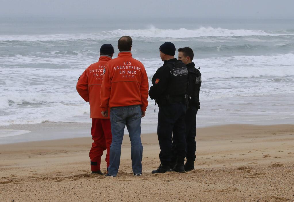 French gendarmes, right, and rescue workers chat during searches for the chief executive of sportswear maker Quiksilver Pierre Agnes, on the beach of Hossegor, southwestern France, Wednesday, Jan.31, 2018. French authorities have deployed boats and helicopters off the coast of southwest France to search for Agnes after his empty boat was found washed ashore Tuesday. (AP Photo/Bob Edme)